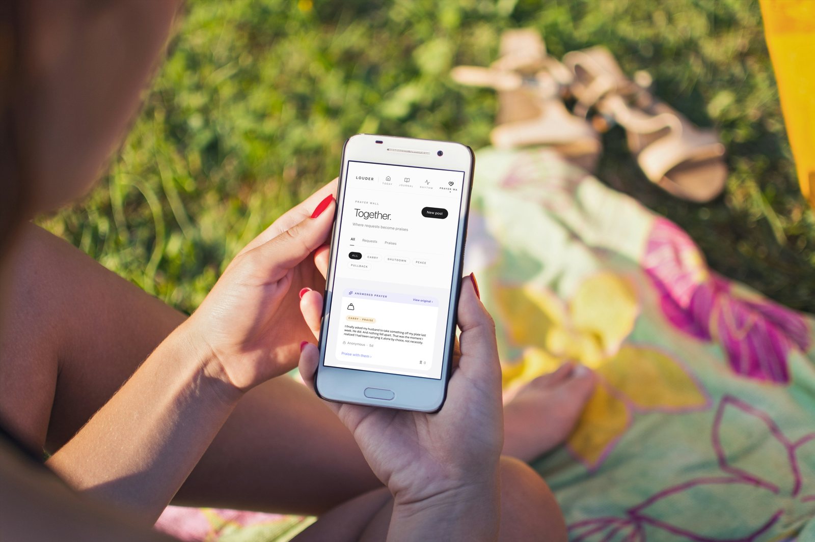 Hands holding a phone open to the LOUDER app’s Prayer Wall